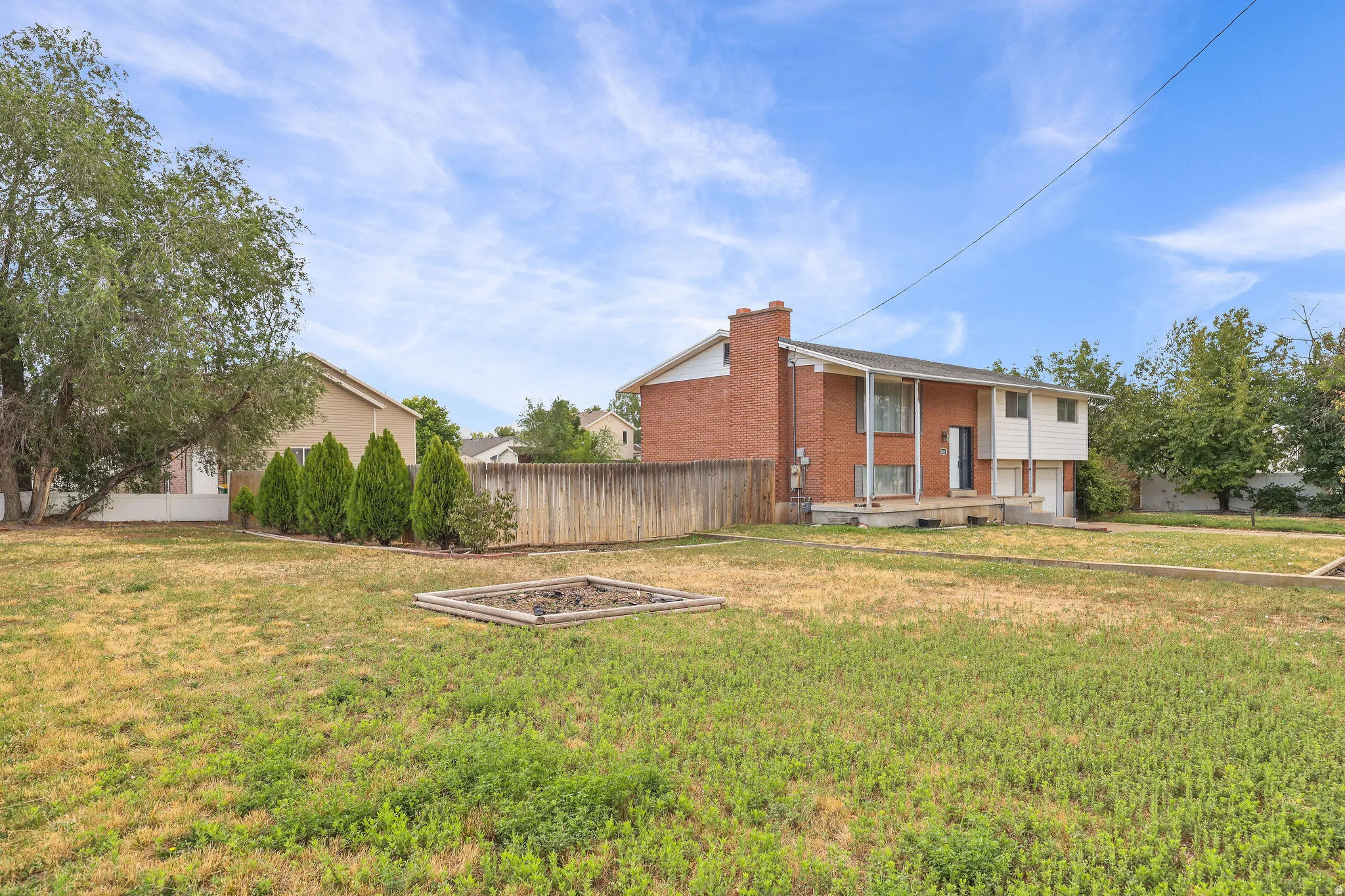 Expansive lawn area featuring a raised garden bed and perimeter fencing