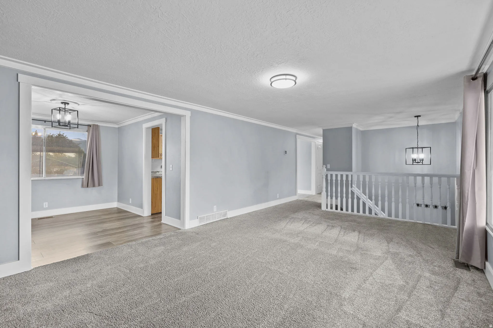 Spacious carpeted area with a white banister and open staircase