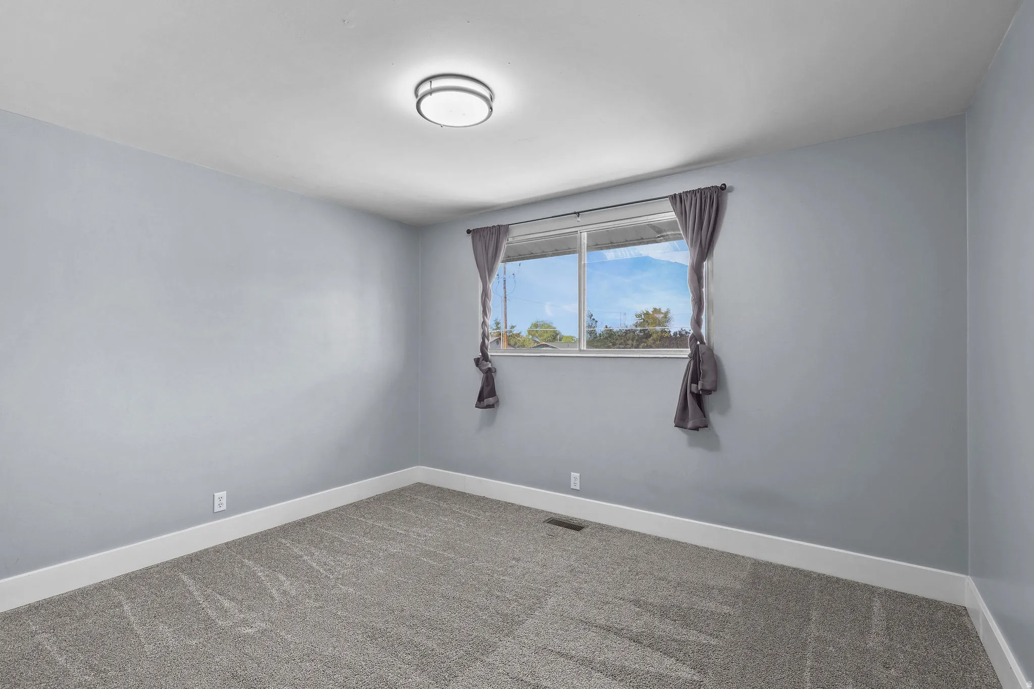 Neutral-toned carpeting, light gray wall finish, and a window with natural light