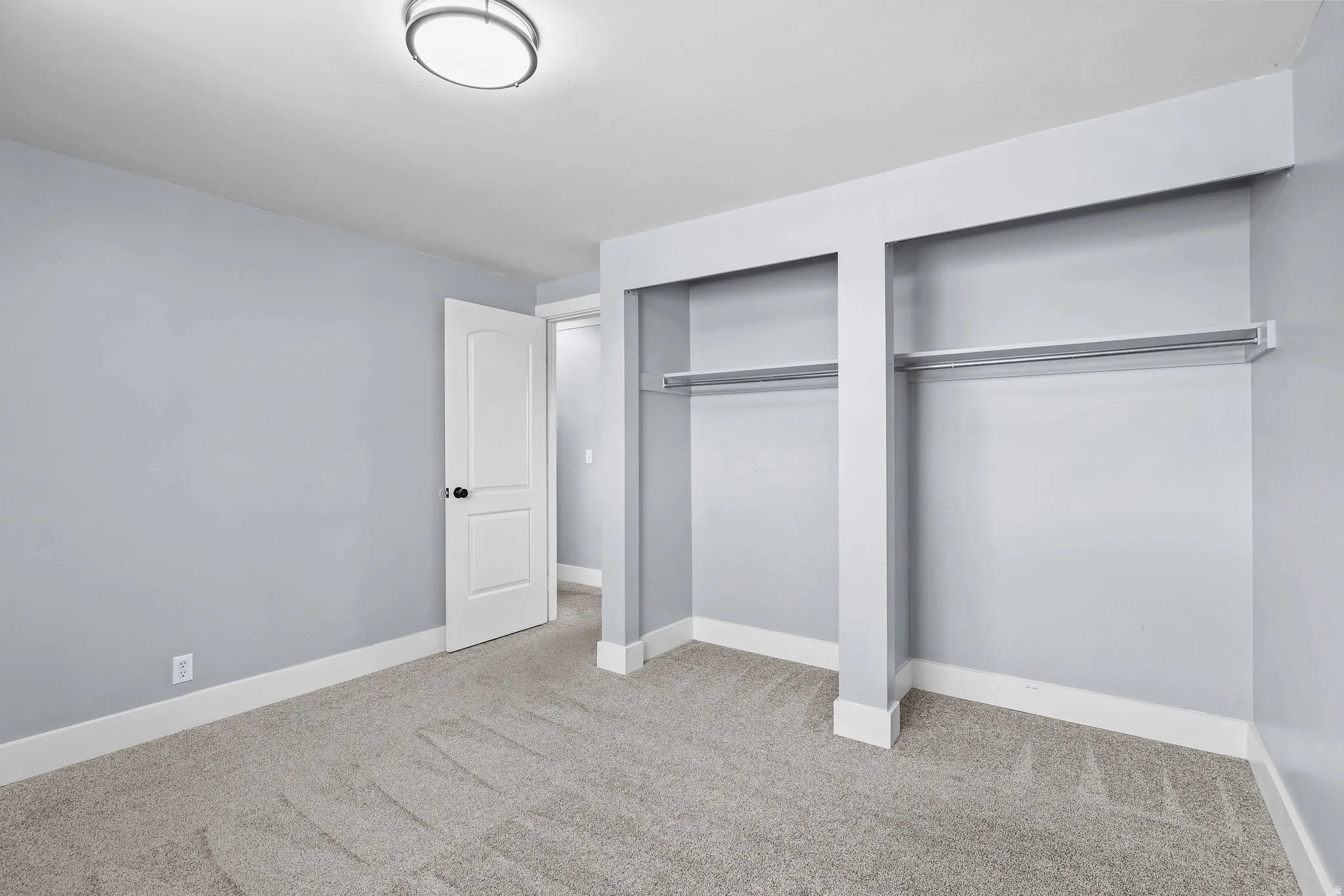 Plush carpet flooring, neutral wall tones, white trim, and a built-in closet with hanging rods