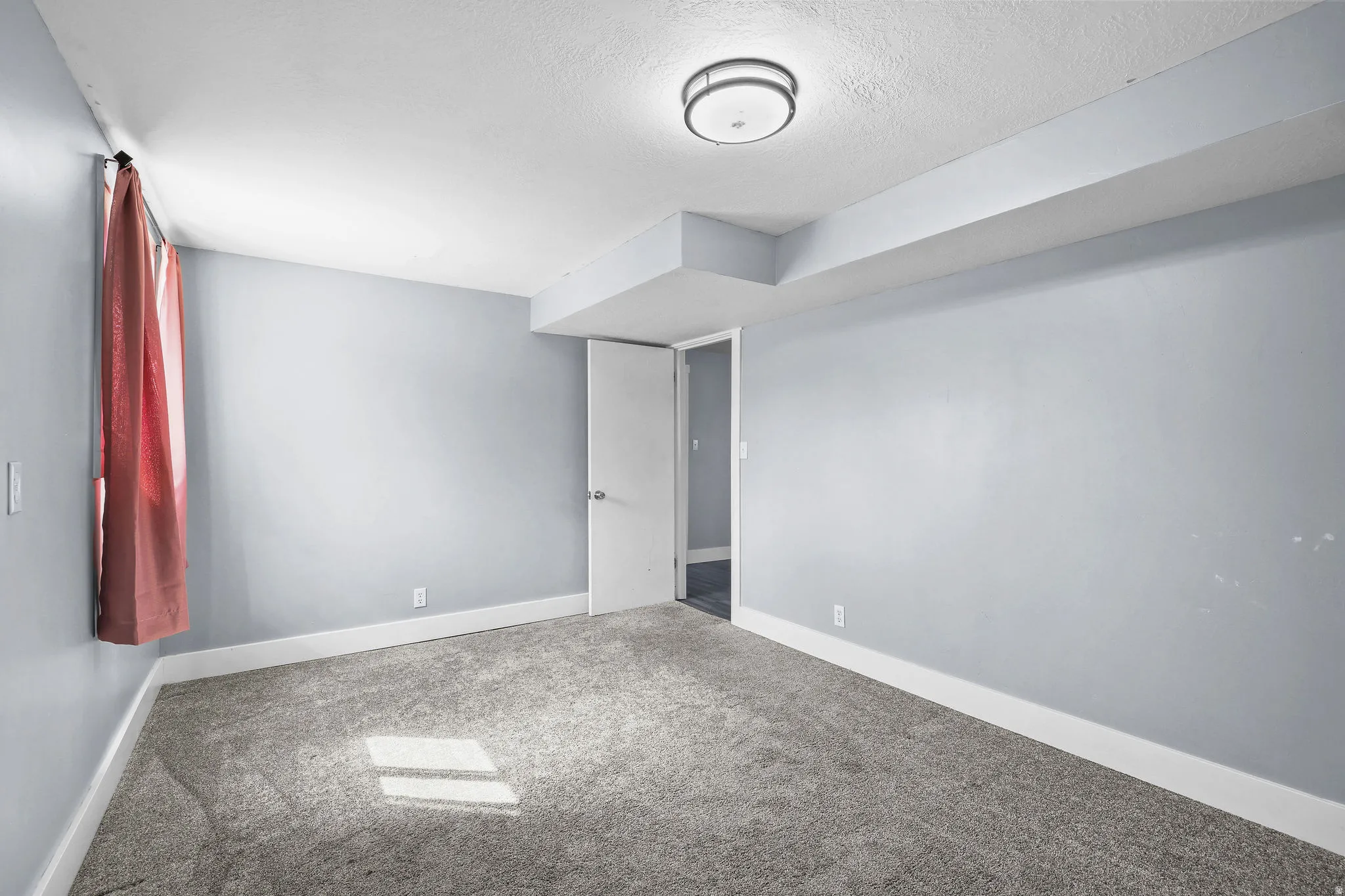 Gray wall-to-wall carpeting, light gray wall paint, and overhead flush-mount lighting