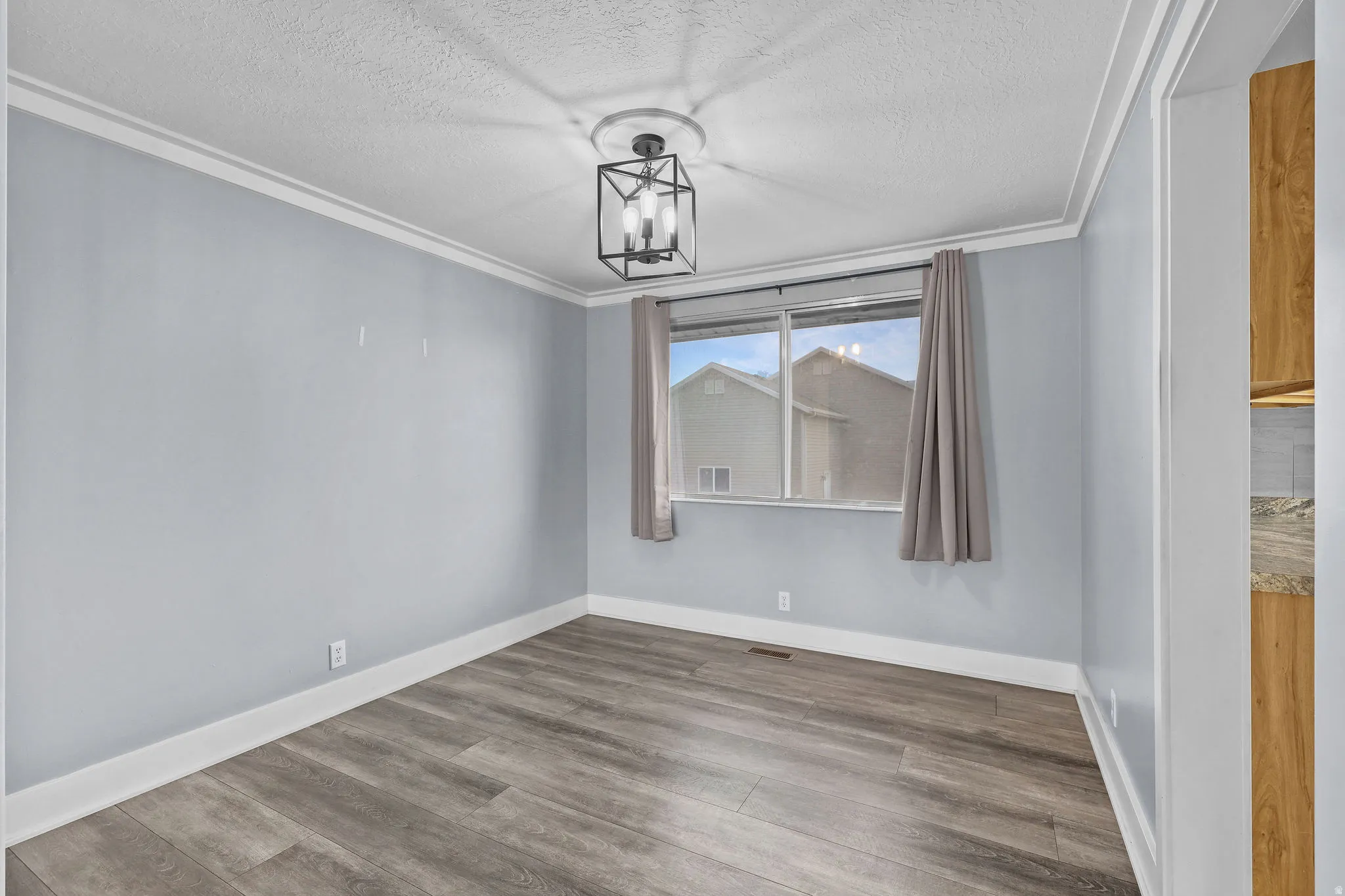 Wood-finish flooring, crown molding, and a modern ceiling light fixture