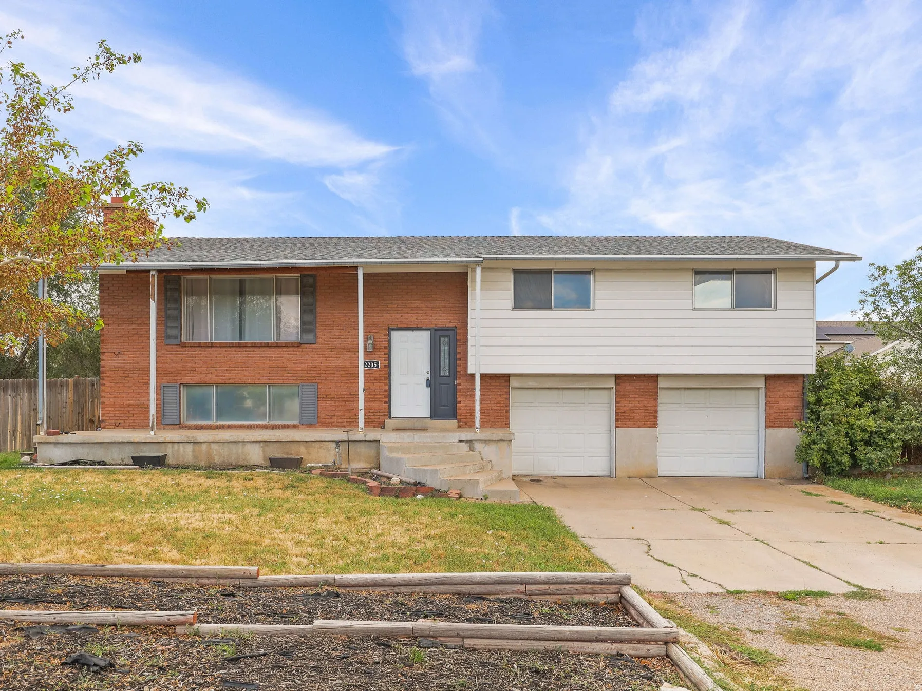 Brick and siding exterior with a two-car garage, front entry, and a tiered planter bed