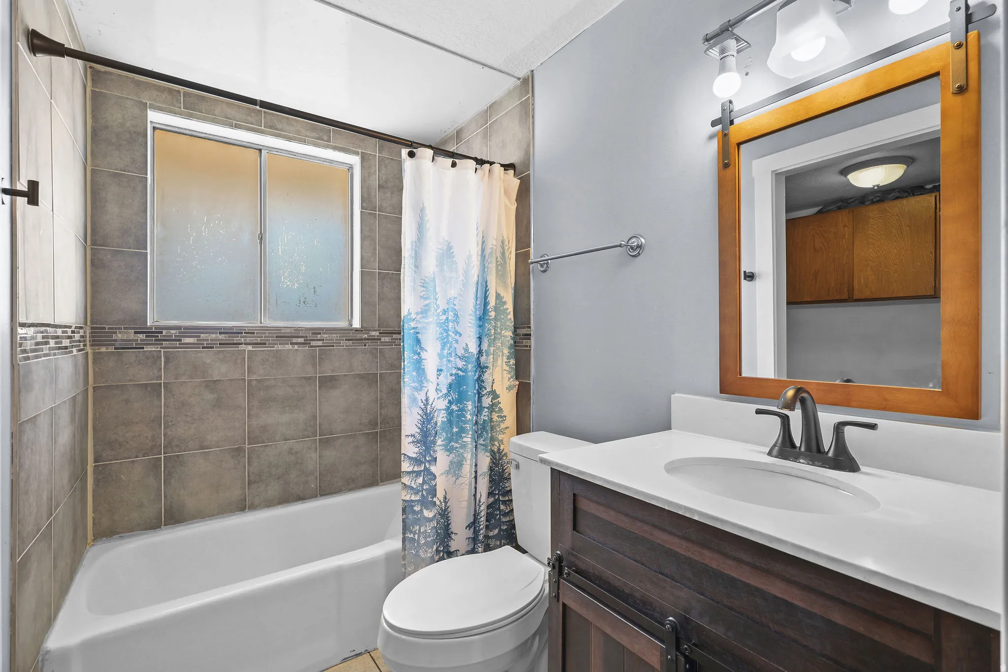 Bathroom with a built-in tub and shower, featuring a tiled surround and mosaic accent band
