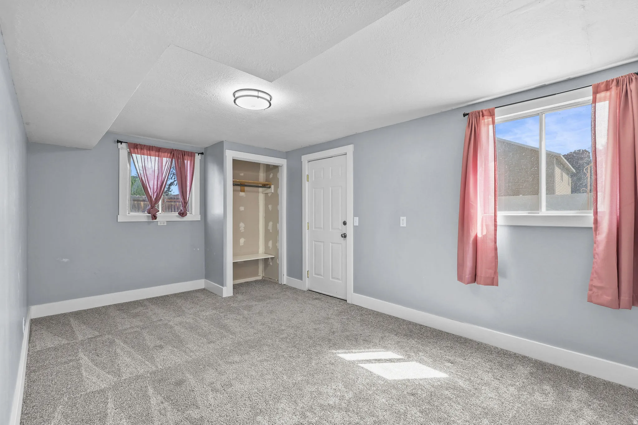 Neutral tone wall finishes, gray patterned carpeting, recessed ceiling light fixture, built-in closet shelving, and a solid core door