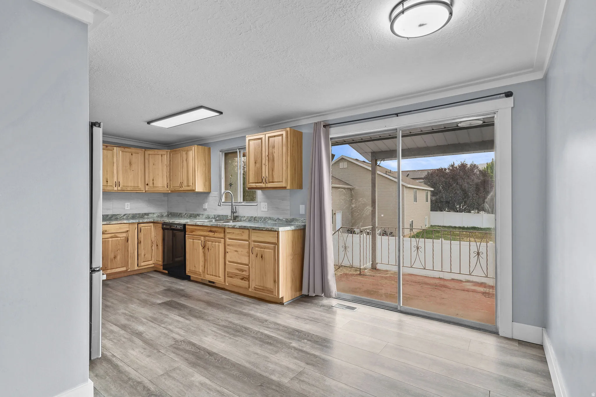 Kitchen with wood cabinetry, light-colored countertops, and a tile backsplash