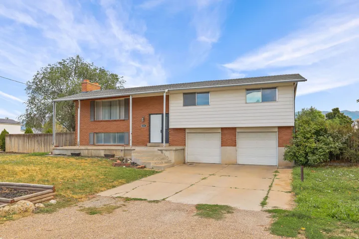 Split-level residence featuring a brick and siding exterior, covered front entry, two-car garage, and a concrete driveway