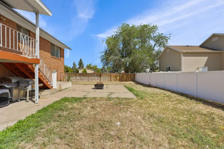 Brick exterior with an elevated deck, concrete patio, and a privacy fence