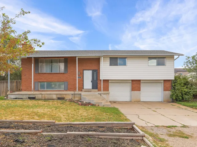 Brick and siding exterior with a two-car garage, front entry, and a tiered planter bed