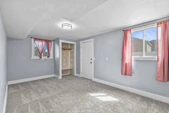 Neutral tone wall finishes, gray patterned carpeting, recessed ceiling light fixture, built-in closet shelving, and a solid core door