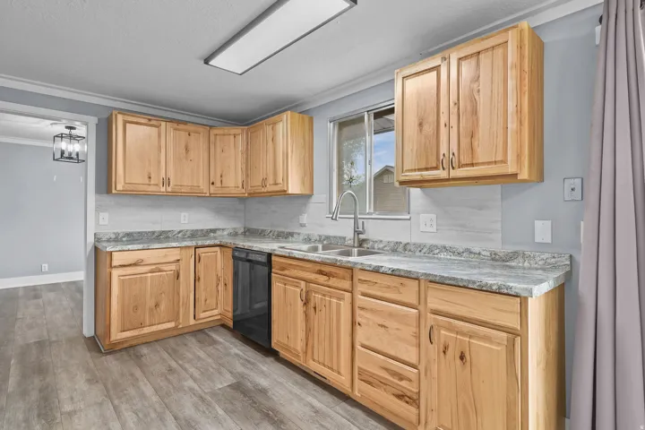 U-shaped kitchen featuring wood-finish cabinetry, light-toned countertops, a stainless steel sink, and wood-finish flooring