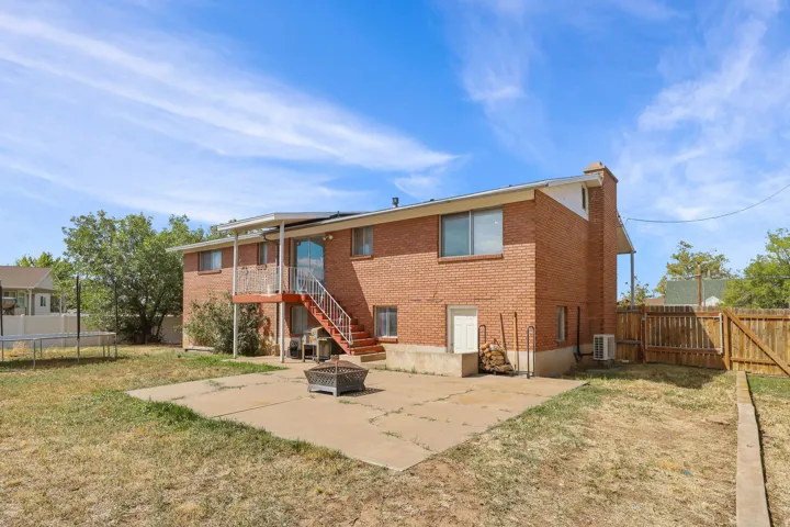 Brick exterior with a second-story balcony featuring metal railings and a covered patio
