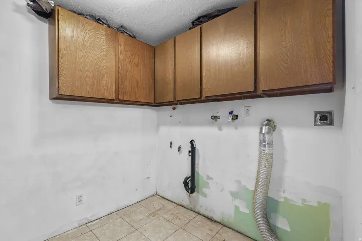 Overhead wood-finish cabinetry, tile flooring, and utility hookups