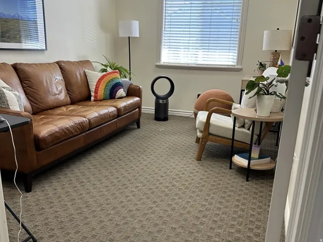 Textured wall-to-wall carpeting, window with horizontal blinds, and cream-colored wall paint