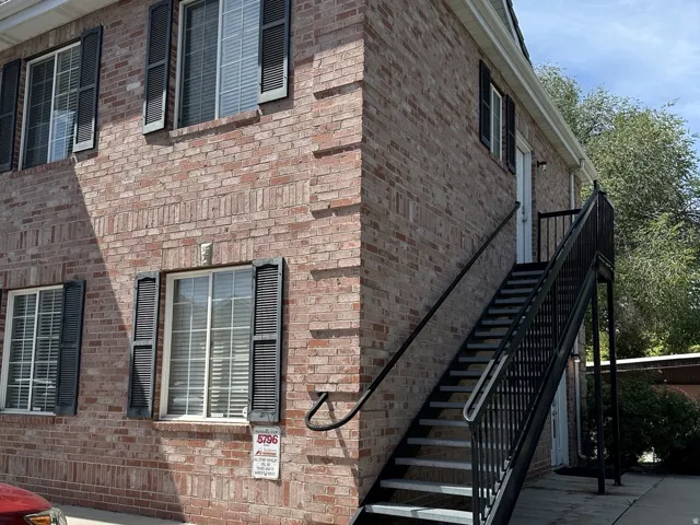 Brick exterior with multiple windows, protective shutters, metal exterior staircase, and a second-level entry