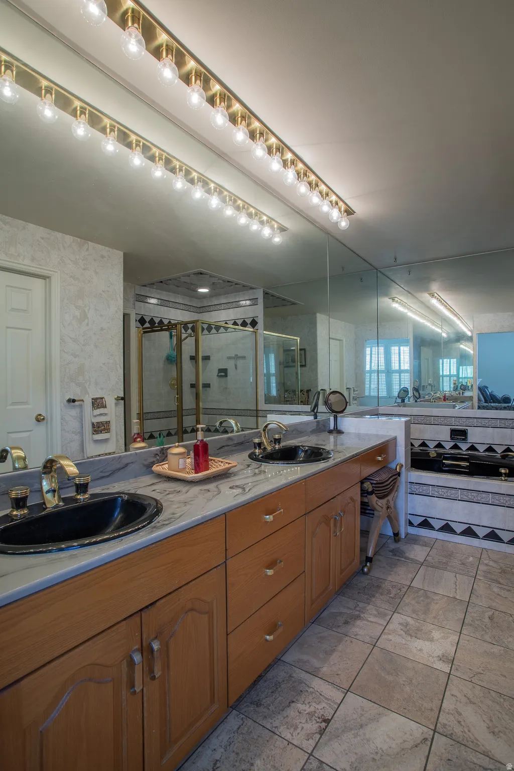 Dual vanity with black vessel sinks, gold-tone fixtures, and a light-toned stone countertop