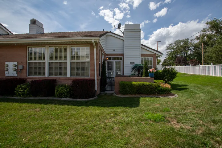 Brick exterior with white trim, multiple windows with blinds, an enclosed entry, and a white picket fence bordering the property