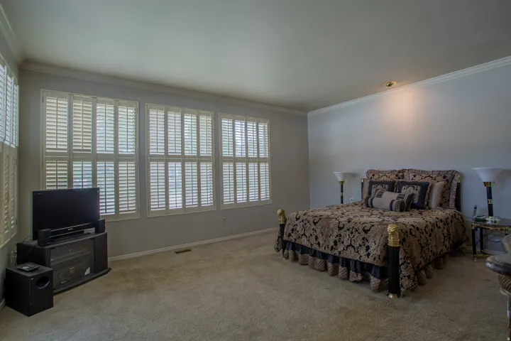 Multiple windows with white plantation shutters, crown molding, and recessed lighting