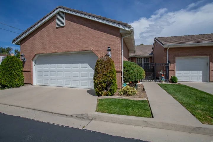 Brick exterior with multiple attached garages, concrete driveways, and manicured landscaping