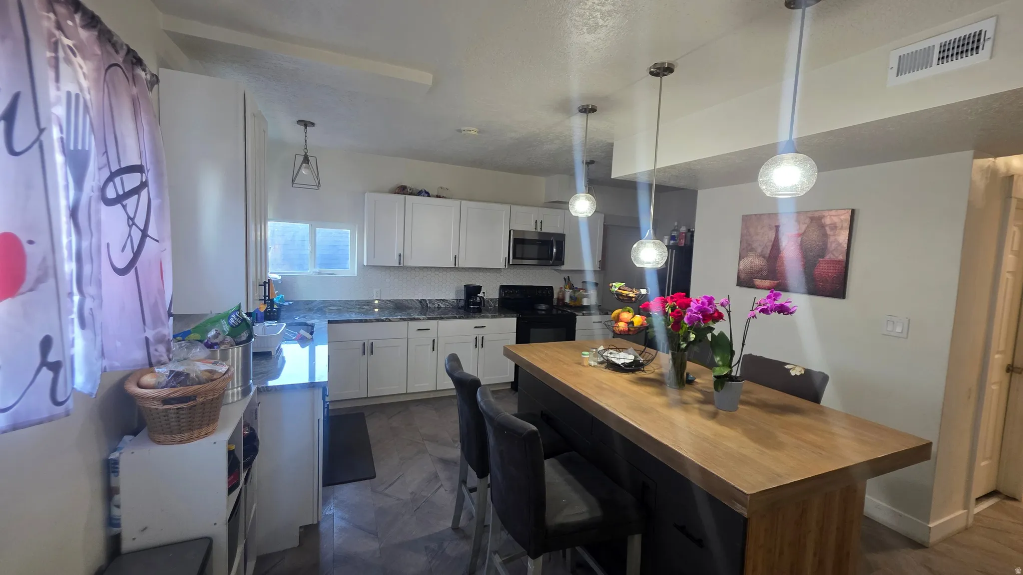 Kitchen featuring white cabinetry, dark countertops, a white tile backsplash, wood-finish flooring, and a central island with an integrated wood-finish countertop