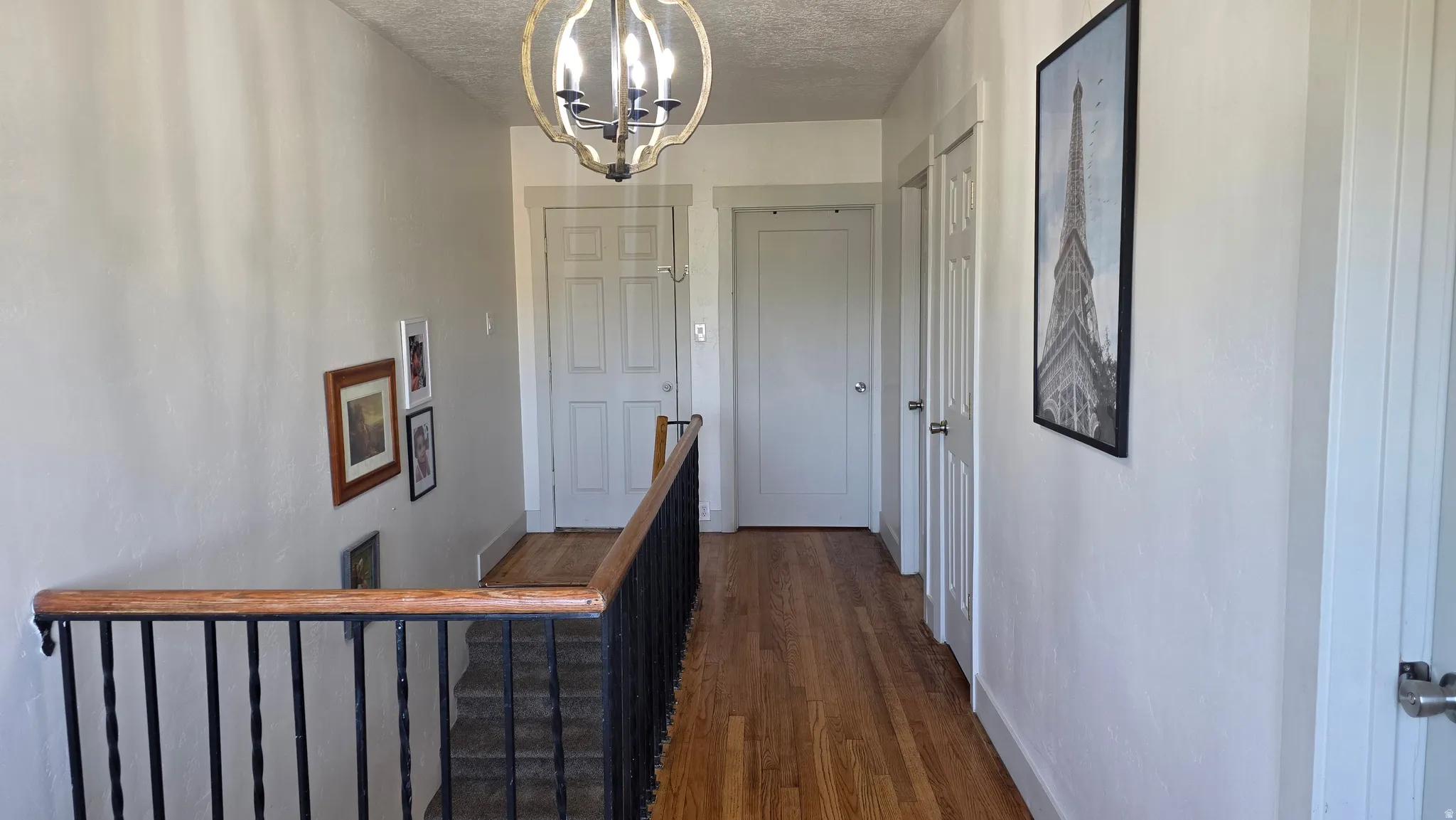 Hardwood flooring, painted interior doors, chandelier, and a wood and metal stair railing