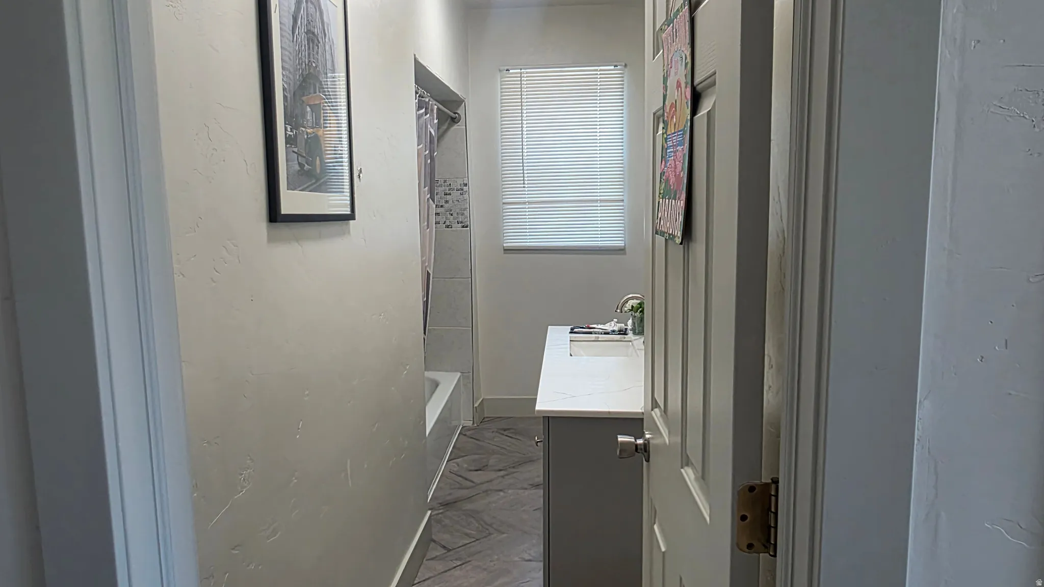 Bathroom featuring a white vanity with an integrated sink, polished chrome faucet, and a window with blinds