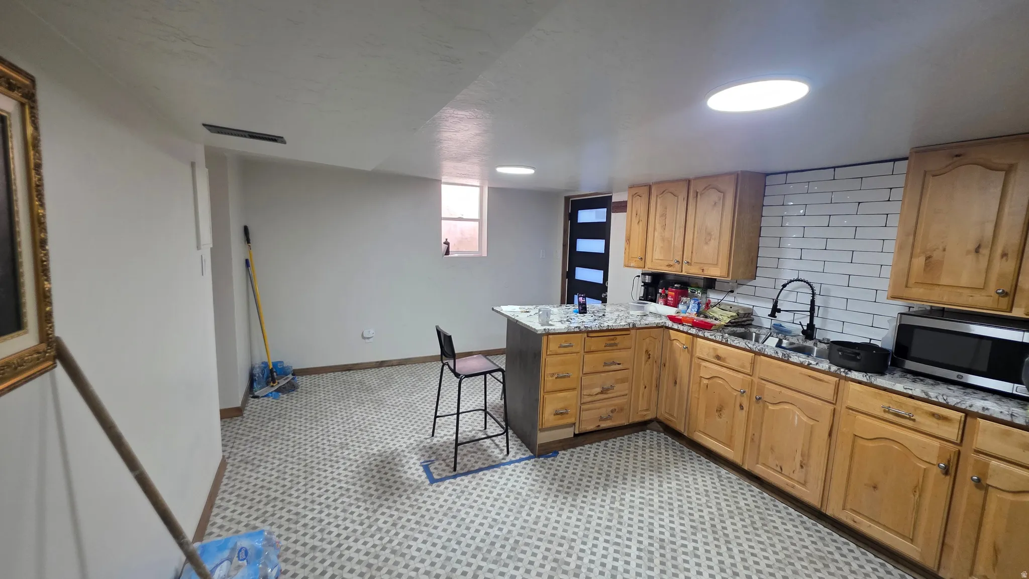 Kitchenette featuring wood-finish cabinetry, white subway tile backsplash, and light-toned countertops