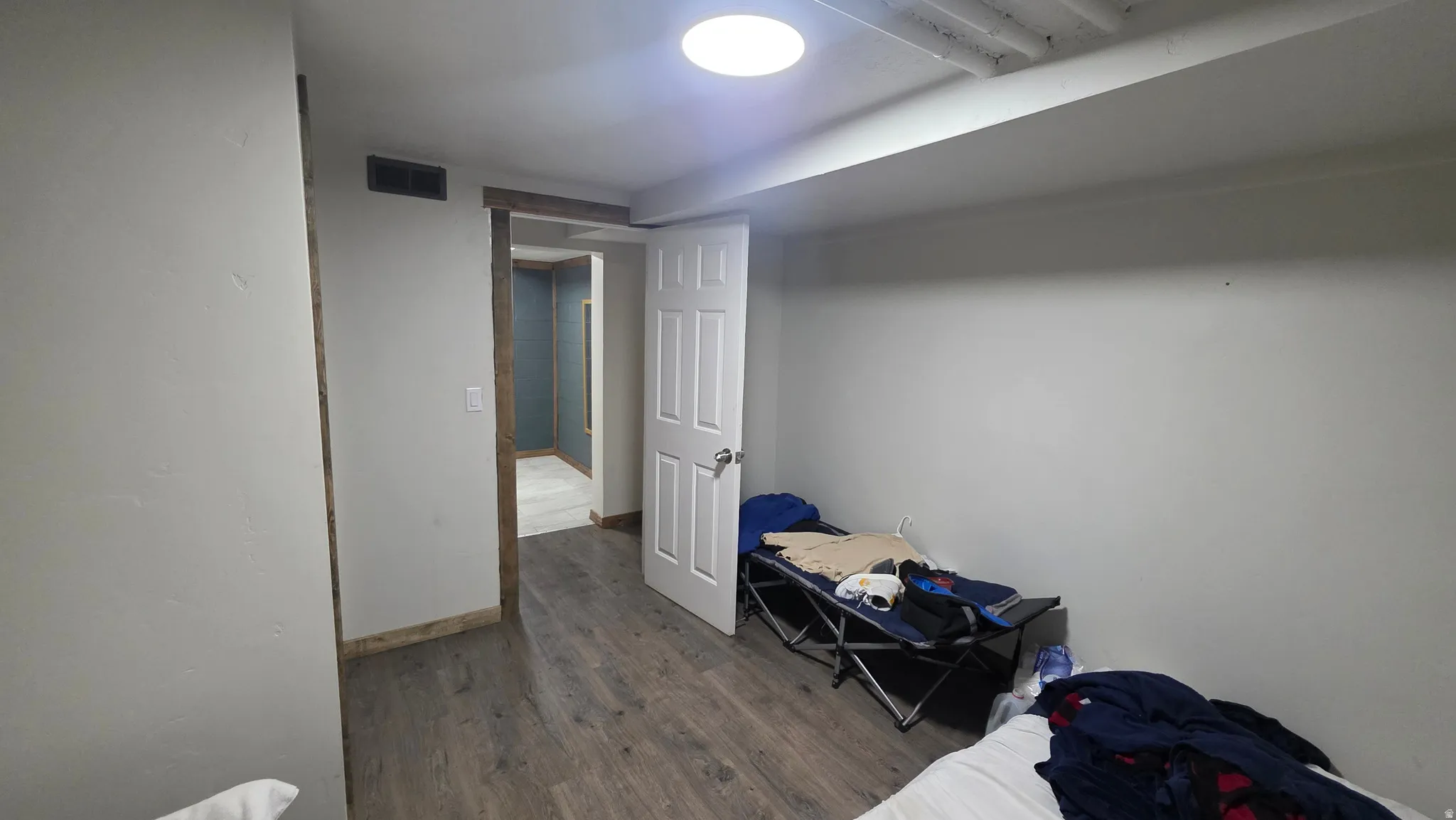 Wood-finish flooring with light-colored walls and a white door