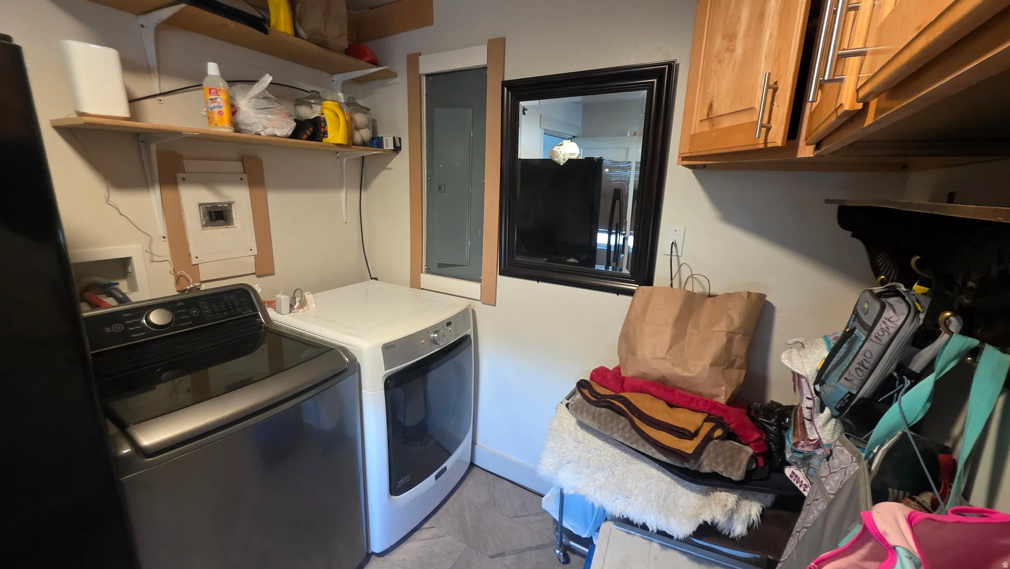 Laundry area with tile flooring and wood-finish cabinetry