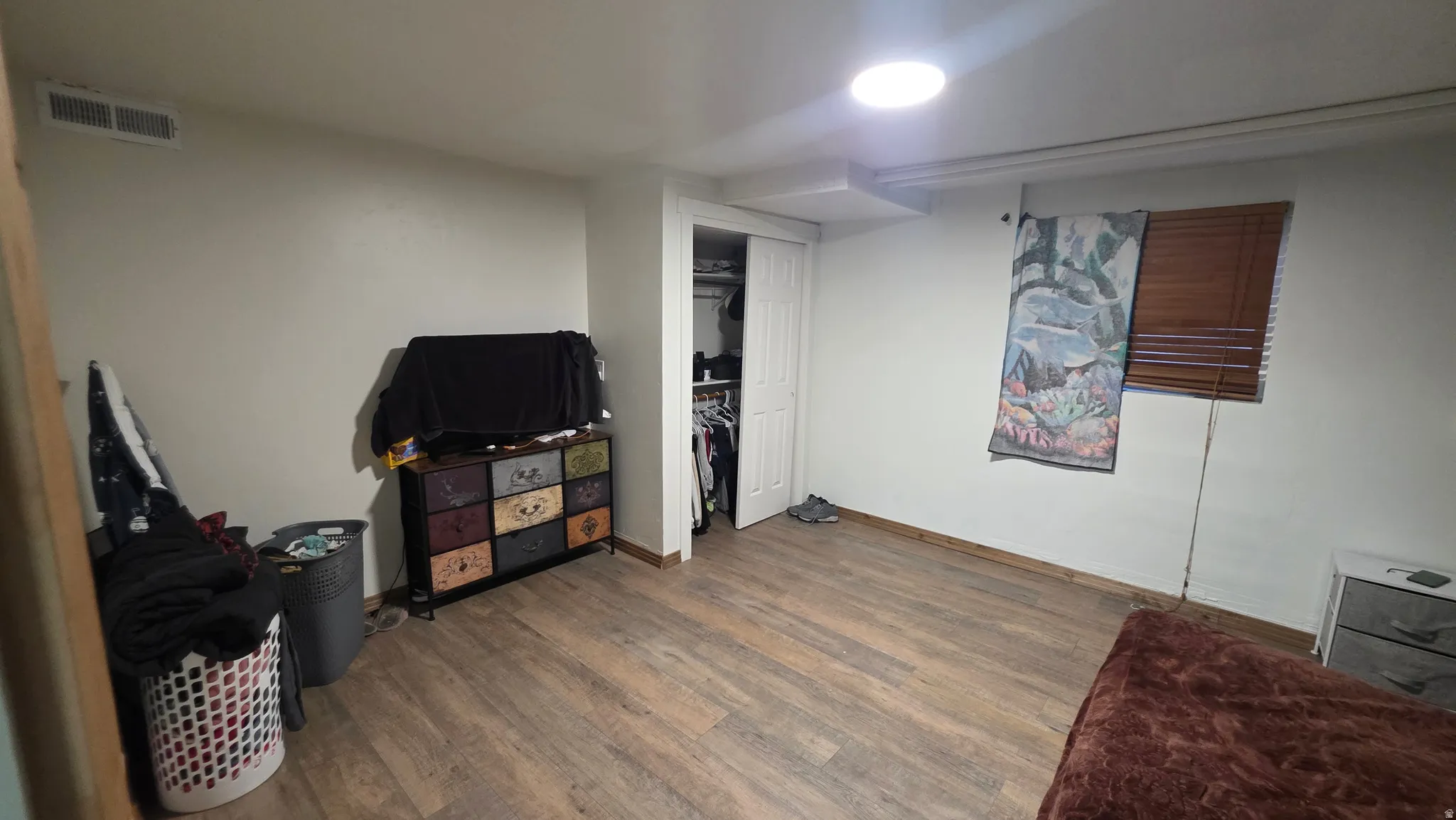 Wood-finish flooring, white painted walls, and a built-in closet with bi-fold doors
