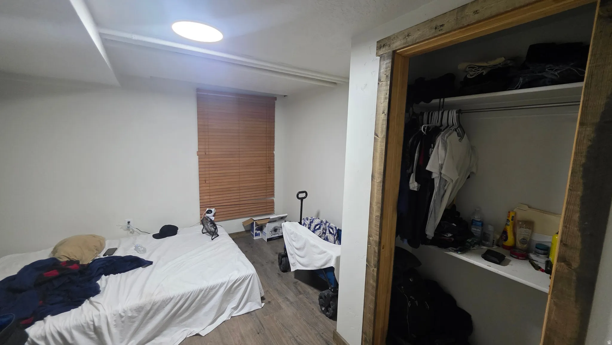 Recessed ceiling light, wood-look flooring, window with wood blinds, wood-frame closet, and built-in closet shelving