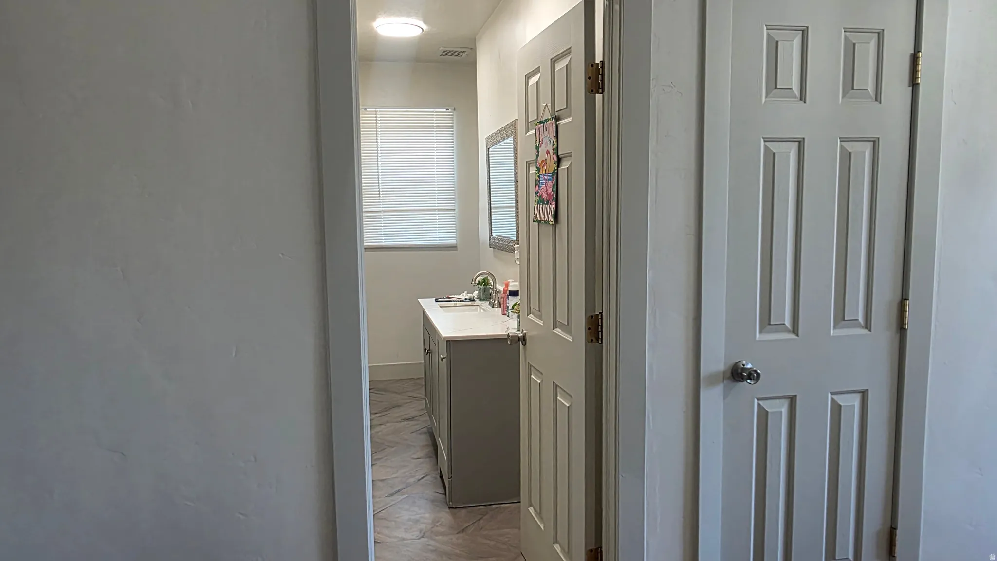 Bathroom featuring a window, vanity with counter, and framed mirror