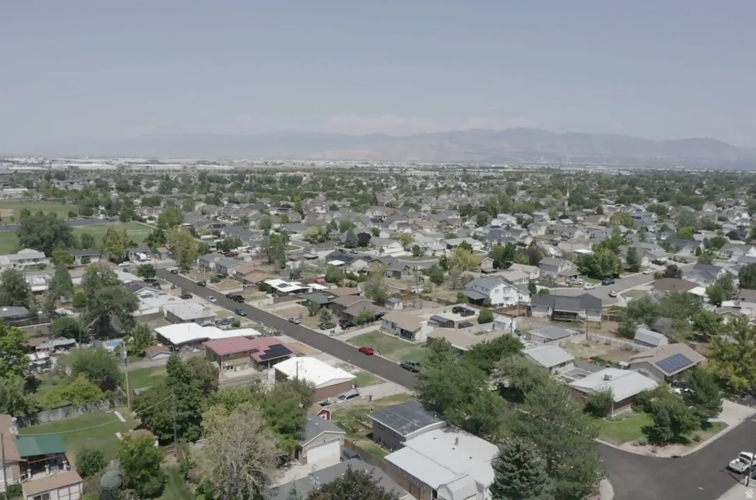 Expansive neighborhood setting with numerous residential properties, mature trees, and mountainous backdrop
