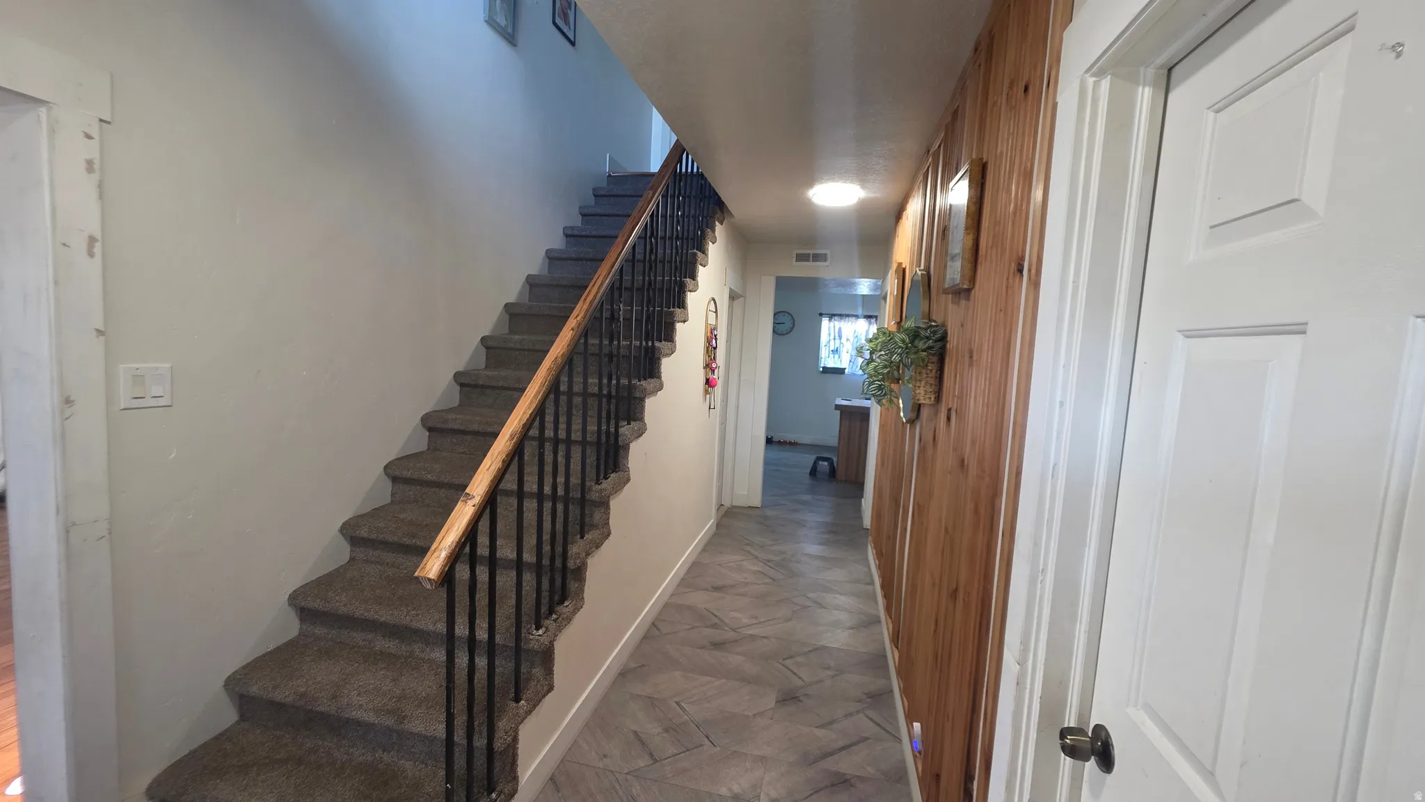 Carpeted staircase with dark metal balusters and wood handrail