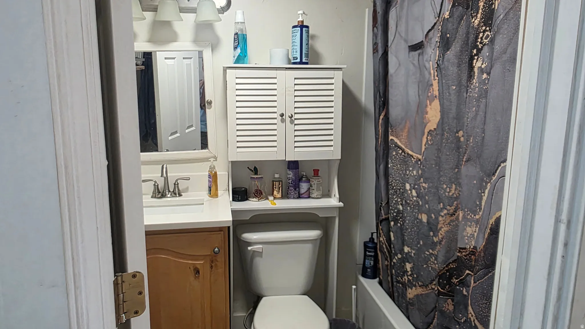 Vanity with a single basin sink, white countertop, and wood-finish cabinetry