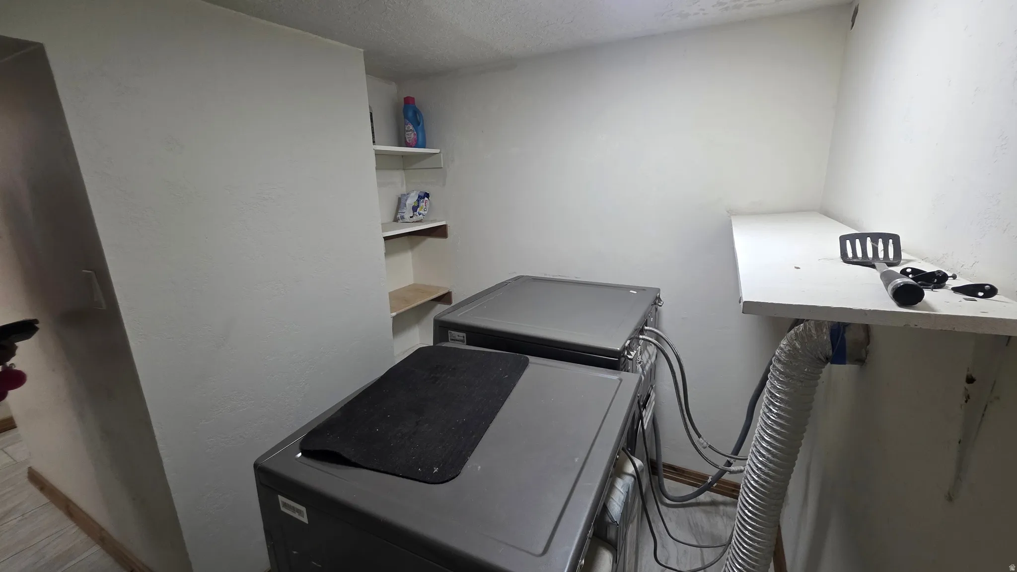 Laundry area with built-in shelving and a wall-mounted countertop