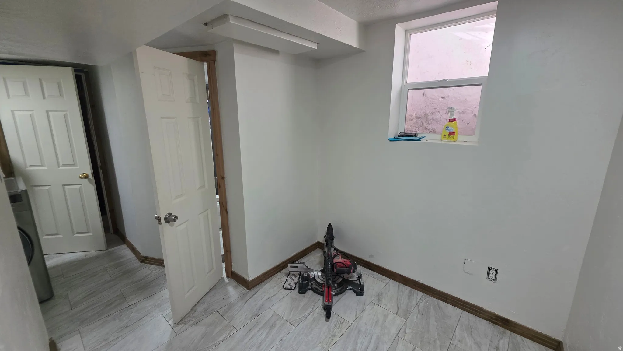 White painted walls, wood-finish baseboards, and light-toned tile flooring