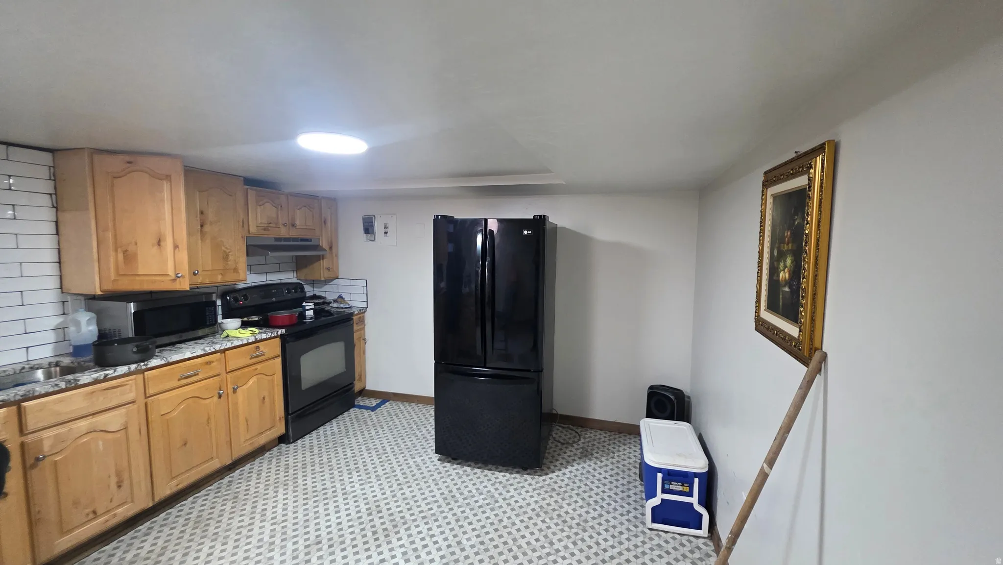 Kitchen featuring light wood cabinetry, white subway tile backsplash, and patterned floor tile