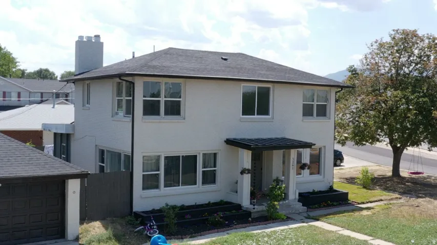 Two-story residence with a dark shingle roof, painted brick exterior, and a covered entryway