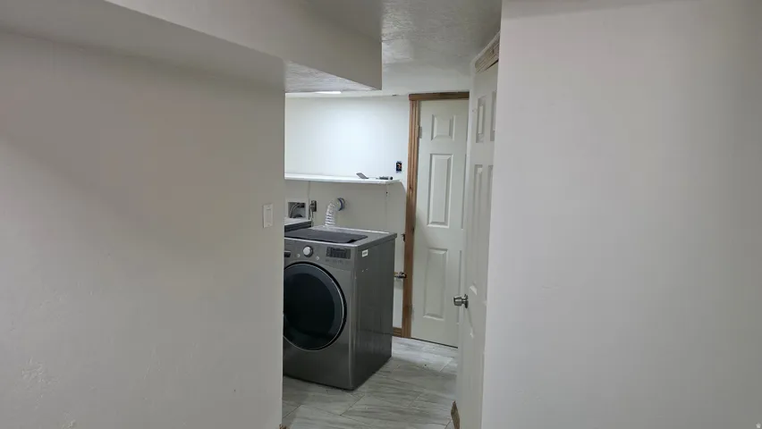 Laundry area featuring a built-in shelf, white paneled door, and light-toned flooring