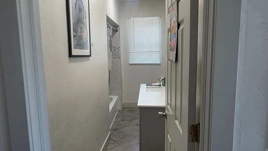 Bathroom featuring a white vanity with an integrated sink, polished chrome faucet, and a window with blinds
