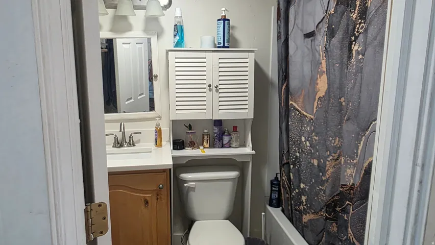 Vanity with a single basin sink, white countertop, and wood-finish cabinetry