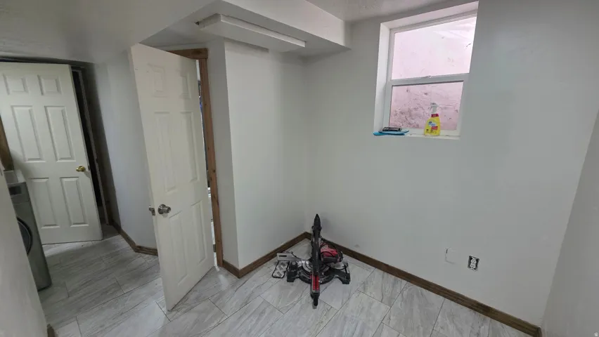 White painted walls, wood-finish baseboards, and light-toned tile flooring