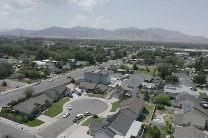 Residential street with cul-de-sac, surrounded by mature trees and distant mountains