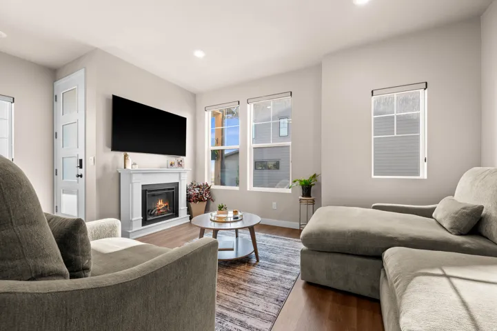 White mantel with an electric fireplace, recessed lighting, and wood-finish flooring