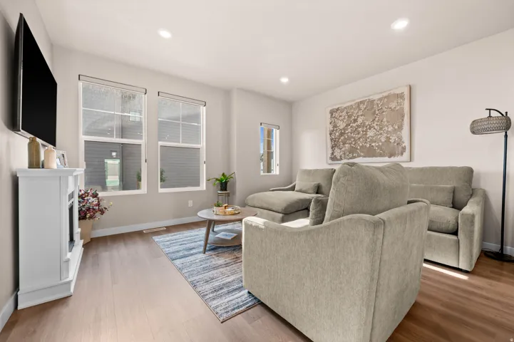 Recessed lighting illuminates the space, featuring wood-finish flooring and multiple windows
