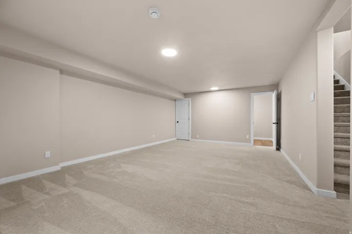 Expansive carpeted floor with recessed lighting and neutral wall tones