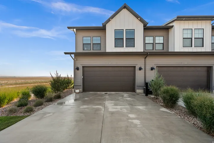 Modern exterior with horizontal and vertical siding, featuring a two-car garage and concrete driveway
