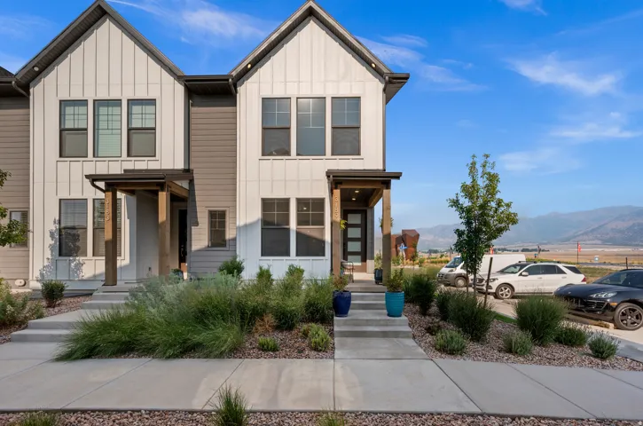 Modern townhome exterior with board and batten siding, covered entry, and black-frame windows