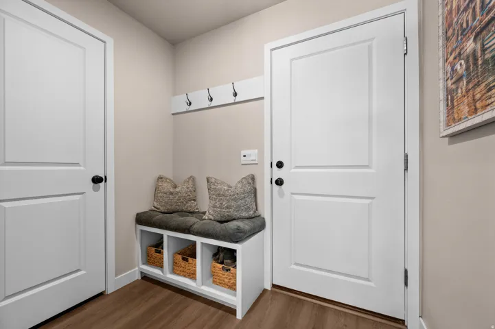 Built-in bench with storage, coat hooks, wood-finish flooring, and crisp white panel doors